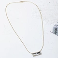 Minimalist gold necklace featuring a rectangular clear gemstone pendant on a textured white background - Gold