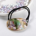 Detail of oval marble acetate hair tie with golden woven metal border and black elastic band - Colorful