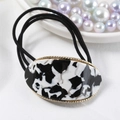 Detail of oval black and white marble pattern hair tie with gold trim and elastic bands - Black & White