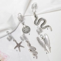 Détail de cinq bijoux de cheveux argentés avec pendentifs étoile, pièce, serpent et ailes - Style Argent Un (M3514)