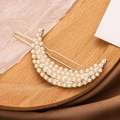 Elegante fermaglio per capelli a luna dorata con perle bianche su sfondo vintage caldo - Stile Perla / Oro