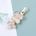 Détail de la pince à cheveux dorée avec deux fleurs élégantes en perles blanches - Style Fleur
