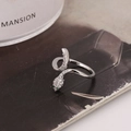 Eleganter Schlangenring aus Silber mit weißen und grünen Zirkonia auf dunklem Papier - Silber