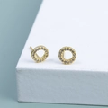 Orecchini a perno circolari dorati con zirconi pavé su un supporto bianco - Stile Oro (A1533)