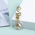 Dettaglio macro di un anello per capelli a serpente dorato con pendente a goccia champagne - Oro Antico Champagne