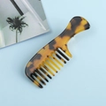 Gros plan détaillé sur une mini pince à cheveux peigne en acétate à motif écaille de tortue - Ambre