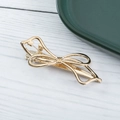 Elegant gold hollow bow metal hair clip shown from a top view on a wooden surface - Golden Bow knot (E1522)