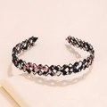 Dettaglio di cerchietto intrecciato nero con accenti in tessuto floreale rosa e luce soffusa - Nero Floreale