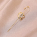 Close-up of gold ear crawler with sparkling rhinestones on champagne satin fabric - C-Shape Gold