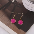 Vista macro de pendientes dorados con dijes redondos de resina en color magenta brillante - Rojo Rosa (B1307)