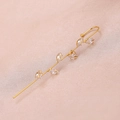 Close-up of golden leaf-shaped ear crawler earring with marquise-cut zircons on pink silk - Leaf Gold