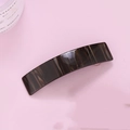 Detail einer dunkel marmorierten Haarklammer mit glänzendem Finish auf rosa Hintergrund - Kaffeestreifen