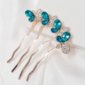 Dettaglio di 4 forcine a farfalla dorate con strass blu su sfondo di seta bianca elegante - Stile Farfalla Blu (I1201)