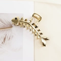 Close-up of golden fishbone hair claw clip featuring a blue rhinestone on a fabric surface - Fishbone Blue Rhinestone Gold
