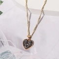 Detailaufnahme einer goldenen Herzanhänger-Halskette mit dunklem Steininlay und Kette - Dunkelgrau D3320