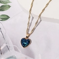 Elegante goldene Kordelkette mit blauem Kristallherz-Anhänger auf weißem Sockel - Dunkelblau D3321