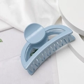 Détail d'une pince à cheveux bleu clair mat sur un fond de tissu blanc minimaliste - Bleu