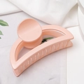 Vista detallada de la pinza para el cabello rosa melocotón sobre tela blanca suave - Rosa