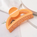 Primer plano de una pinza para el pelo naranja brillante en una base blanca pura - Naranja