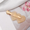 Primer plano de pinza para el pelo con doble corazón sobre tela de seda blanca - Amarillo