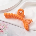 Détail d'une pince à cheveux orange en forme de queue de sirène sur tissu en soie blanche - Orange