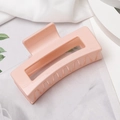 Detail of pink rectangular jelly hair claw clip with a glossy finish on white fabric - Pink