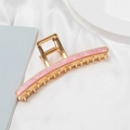 Detail of golden metal claw clip with pink marble resin inlay on white silk fabric - Pink