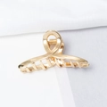 Detailed macro view of a shiny gold metal hair claw clip with a strong spring and teeth - Cross Twist Style (E2525)