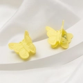 Détail de pinces à cheveux papillon jaunes mates avec texture givrée sur fond de soie - Jaune clair