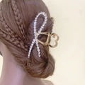Eleganter Haarklammer-Schleifenknoten aus Goldmetall mit Strasssteinen auf braunem Haar - Schleife (Strass) / Gold