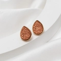Detailed macro view of orange pink teardrop druzy earrings with gold textured edges - Rust Red