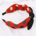 Vue détaillée d'un serre-tête rouge à pois avec un nœud noir sur tissu blanc - Rouge à Pois (E1115)