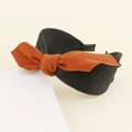 Dettaglio di un cerchietto nero largo con un fiocco in tessuto arancione bruciato - Nero (E1114)