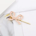 Détail d'une barrette à cheveux nœud en émail rose avec bords dorés polis sur fond blanc - Épingle à cheveux / Rose