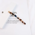 Detail view of a slim tortoiseshell acetate hair clip with vintage patterns on white packaging - Dark Leopard Print