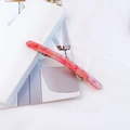 Close-up of a pink marble acetate spring hair clip on a white minimalist background - Pink