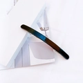 Detail of a minimalist black acetate hair clip with a glossy mirror finish on a magazine - Black