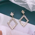 Orecchini geometrici a rombo in oro con cristalli scintillanti su un vassoio decorativo - Stile Rombo Geometrico / Oro