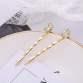 Macro view of gold wave hair clips with rectangular zircon stones on a ceramic plate - Wave Inlaid Zirconia Style (B5215) / Gold
