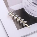Eleganter goldener Haarclip in Blattform mit Marquise-Kristallen auf Magazin - Gold
