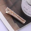 Eleganter goldener Haarclip mit vier Reihen funkelnder Strasssteine auf einem Magazin - Weiß (C1309)