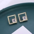 Macro di orecchini a perno quadrati dorati con zircone su vassoio in ceramica - Oro