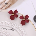 Detailed macro view of matte red floral earrings with gold stamens on a lace decorative plate - Burgundy
