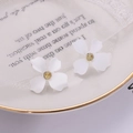 Macro detail of white four-petal flower earrings with golden core on lace cloth - White
