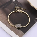 Detail of a gold hexagon druzy bracelet with lobster clasp on a stylish magazine - Grey Gold Base