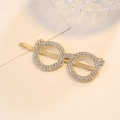Elegante pinza para el pelo con gafas doradas y pedrería brillante en fondo beige - Horquilla / Dorado