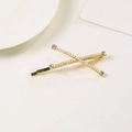 Elegante pinza dorada en X para el pelo con perlas y strass de colores en fondo blanco - Dorado