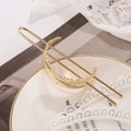 Elegante fermaglio per capelli in metallo dorato con piuma su un piatto di ceramica - Oro