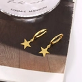 Detailed view of polished gold star dangle hoop earrings on a decorative glass tray - Smooth Five-pointed Star Style