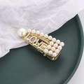 Golden duckbill hair clip with white pearls forming the word LOVE on a green tray - Letter Drop Style